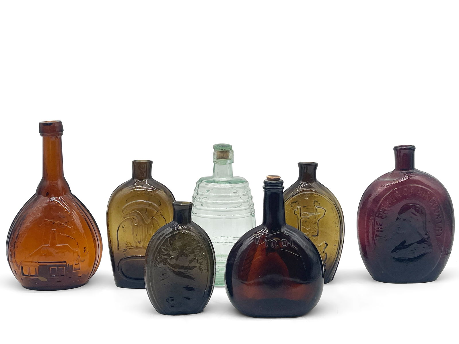 Six Early American Glass Bottles: To include a The Father of His Country/Gen. Taylor Never Surrenders amethyst flask, a Success to the Railroad olive green flask, an amber wine bottle with cork, a Jenny Lind Fislerville Glassworks amb