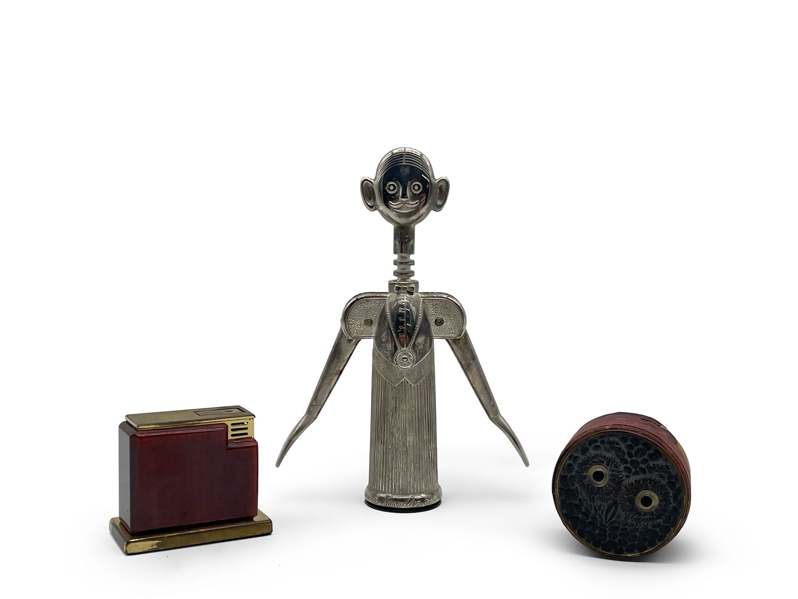 Aldo Columbo Sommelier, Lighter and Shot Glass: An Aldo Colombo chrome sommelier wine opener, an Art Deco lighter with a Bakelite case, and a collapsible jigger with a leather and brass owl-form traveling case. Columbo Sommelier: 8-1/2in tall. | Yo