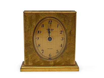 Hermès Paris Alarm Clock and Case: An Hermès Paris clock in a gilt metal Art Deco-styled case with Swiss made alarm, and with original Hermès suede and satin lined traveling case. Clock: 2in tall x 2in wide. | You have additional shi
