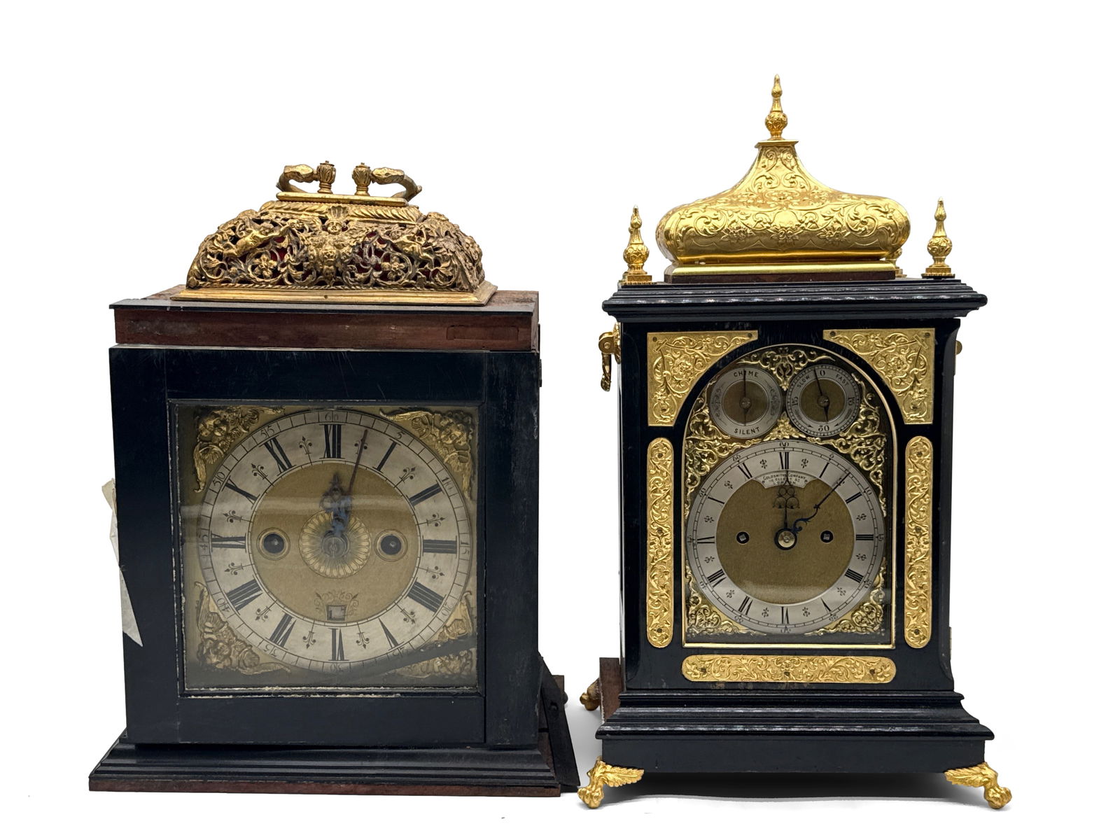 Two Mantel Clocks: Thomas Power and Goldsmith Co.: Grouping with a Thomas Power Wellingborough clock with mahogany case and ornate cherub topped finial, signed on movement; and a Goldsmiths Company, London clock with ornate brass decoration, pendulum