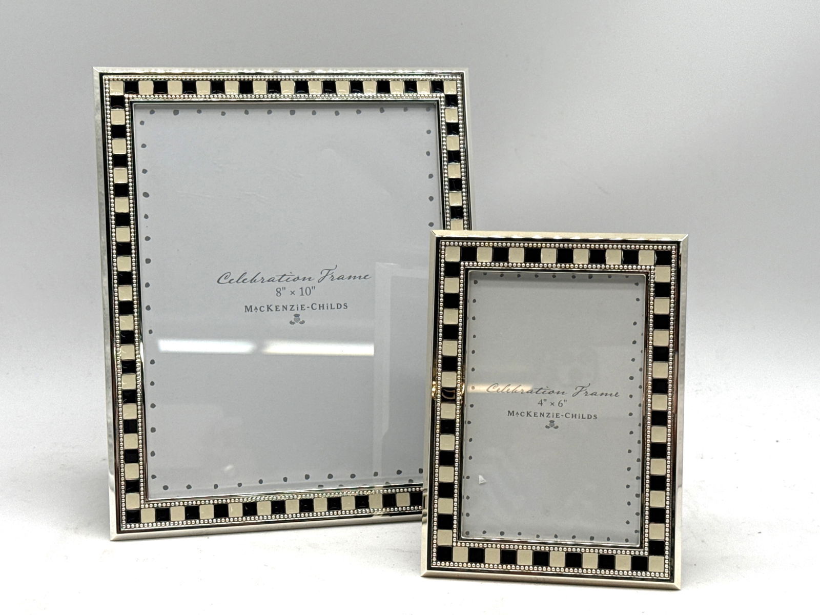 Two MacKenzie-Childs Celebration Picture Frames: Two MacKenzie-Childs Celebration picture frames with black and white enameled border. Each marked MacKenzie-Childs. Larger frame is for 8 x 10in photos. | You have additional shipping options, and are