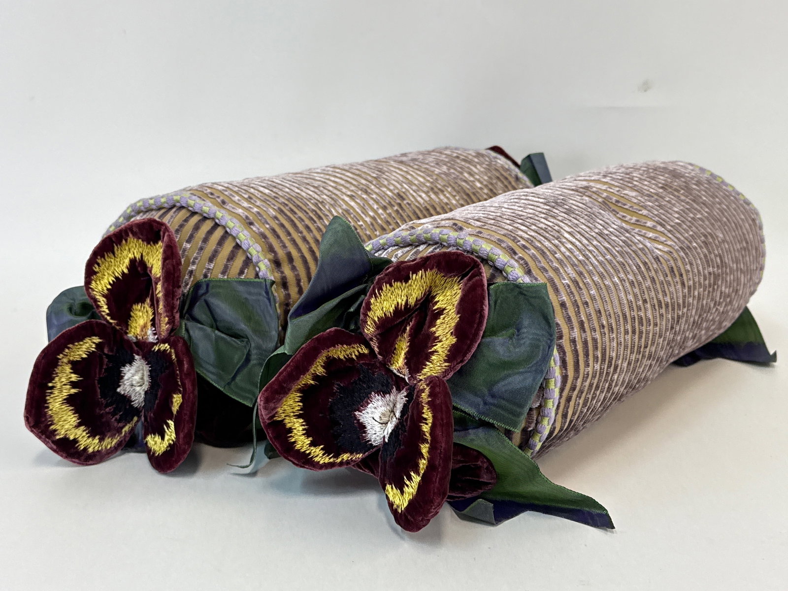 Two MacKenzie-Childs Pansy Petal Bolster Pillows: Two MacKenzie-Childs pansy petal bolster pillows. Each: 6in tall x 18in wide. | You have additional shipping options, and are not required to use Live Shipping. Additional third-party shipper details;