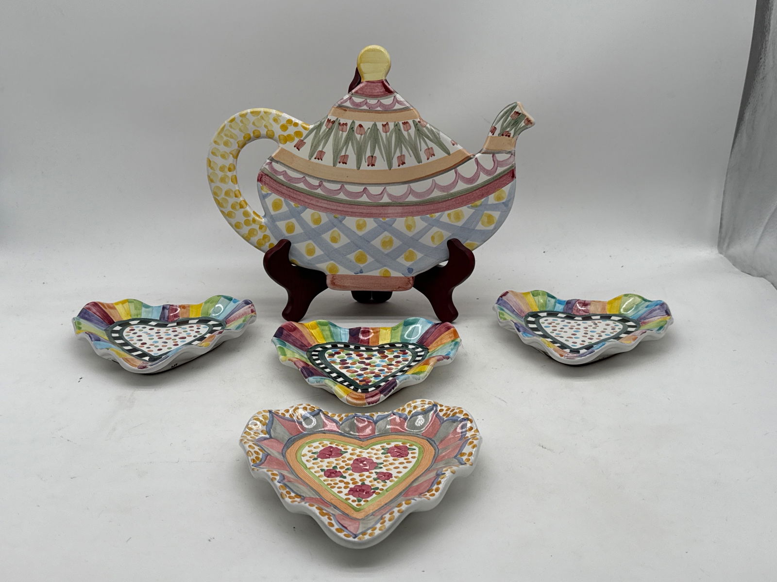 MacKenzie-Childs Teapot Trivet and Heart Dishes: A MacKenzie-Childs ceramic teapot-form trivet and four heart-shaped dishes. Teapot trivet: 9in tall x 12in wide. | You have additional shipping options, and are not required to use Live Shipping. Addi