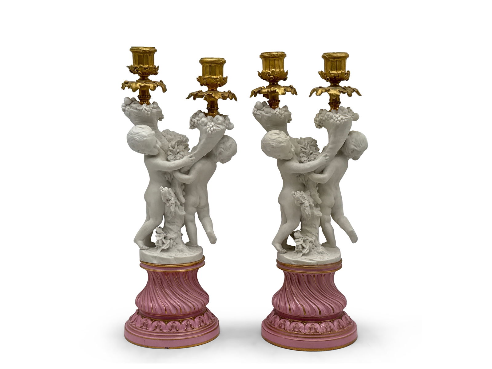 Pr. Sevrès Porcelain, Bisque, Gilt Bronze Candelabra: A pair of Sevres gilt bronze-mounted candelabra modeled as bisque porcelain dancing cherubs holding twin gilt bronze candle arms, on twisted pink porcelain bases. Marked "Dore a Sevres". Provenance: F