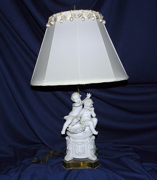 Parian Porcelain Figural Lamp: Parian porcelain figural lamp with pair of cherubs on pedestal base. Unmarked. 26" tall. (50-100)