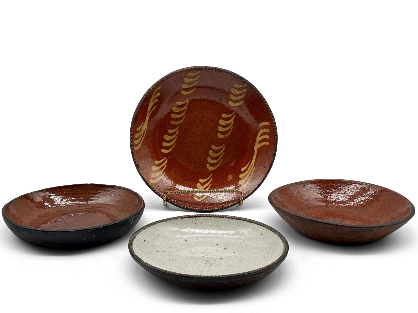 Four Pieces of Pennsylvania Redware: A grouping of 19th C. Pennsylvania redware pottery to include two redware glazed bowls, a cream-glazed redware bowl, and a redware plate with yellow slip decoration. Largest: 10in diameter. | You have