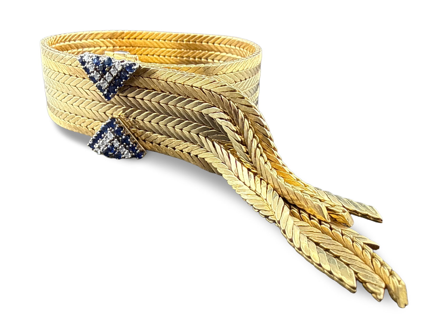 18K Cuff Bracelet with Diamonds and Sapphires: An 18K yellow gold adjustable cuff bracelet comprised of eight woven strands and a double belt buckle-style clasp adorned with diamonds and sapphires. Marked Swiss Made and 750, with HP hallmark. 10-1