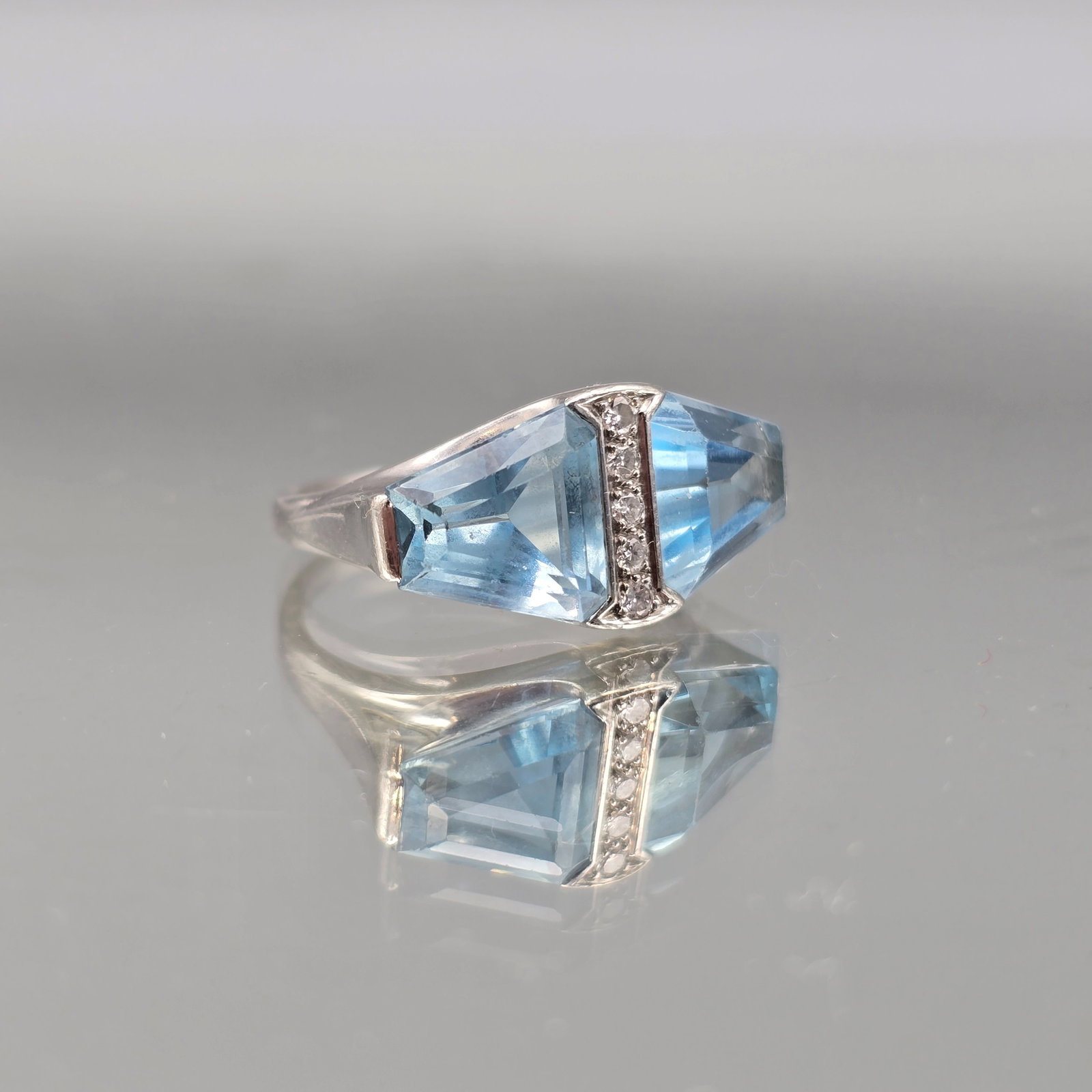 Platinum, Aquamarine, and Diamond Ring: A platinum cocktail ring with two large triangular cut aquamarines flanking five channel-set round cut diamonds. Marked Plat. Ring size 7-1/2. 6.75 dwt. | You have additional shipping options, and