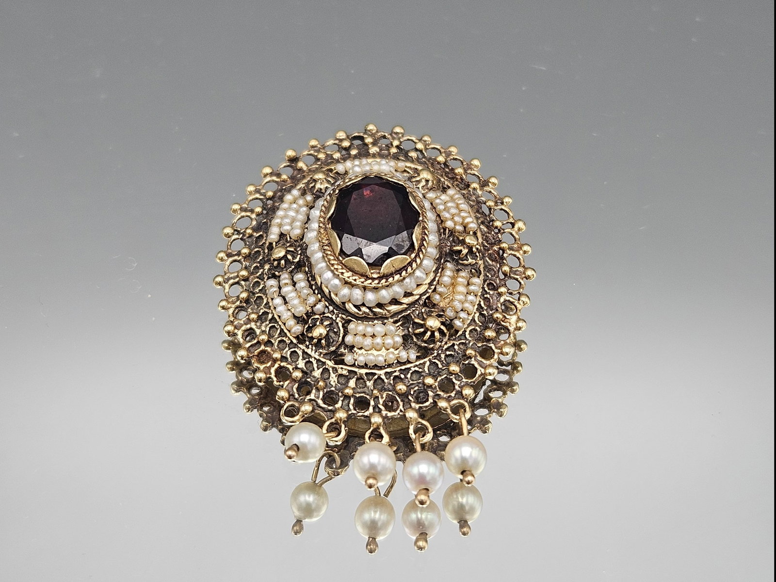 Victorian 14K Garnet and Seed Pearl Brooch/Pendant: A Victorian 14K yellow gold brooch/pendant with a central oval garnet and seed pearls. Unmarked. 1-1/2in x 1-1/8in. 5.65 dwt. | You have additional shipping options, and are not required to use Live
