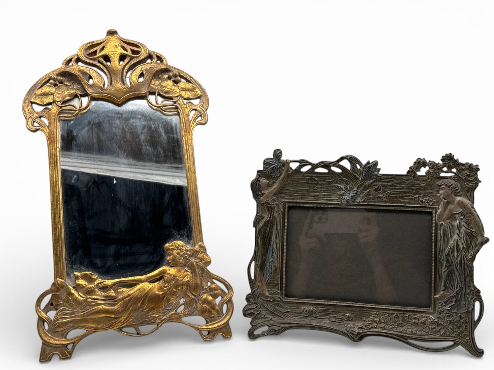 Art Nouveau Figural Mirror and Frame: A gilt-wood Art Nouveau mirror with reclined figural decoration and a painted cast iron frame flanked by figures and flowers. Mirror: 20in tall x 12in wide. | You have additional shipping options, and