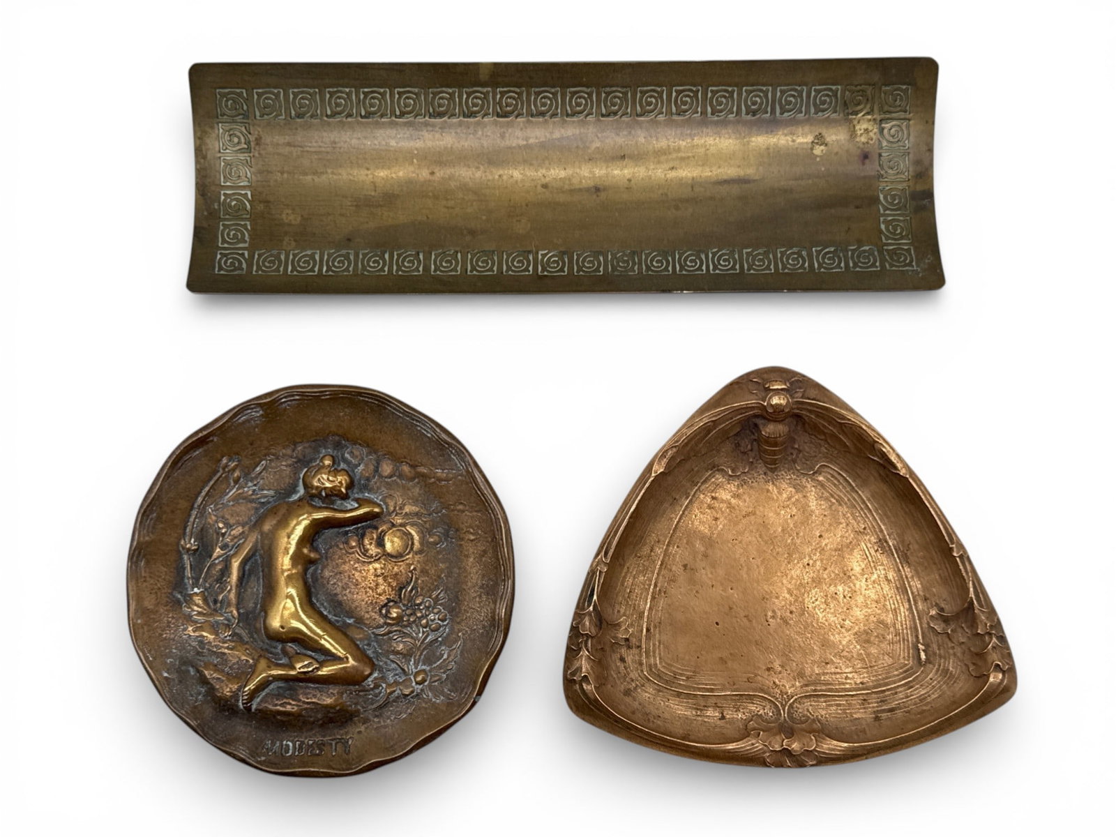Three Bronze Art Nouveau Trays and Plaque: Three bronze Art Nouveau items to include a Gorham triangle-form fish with bee motif, a bronze plaque with Modesty figural motif, and a Bradley & Hubbard bronze pen tray with scroll design. Largest: 3