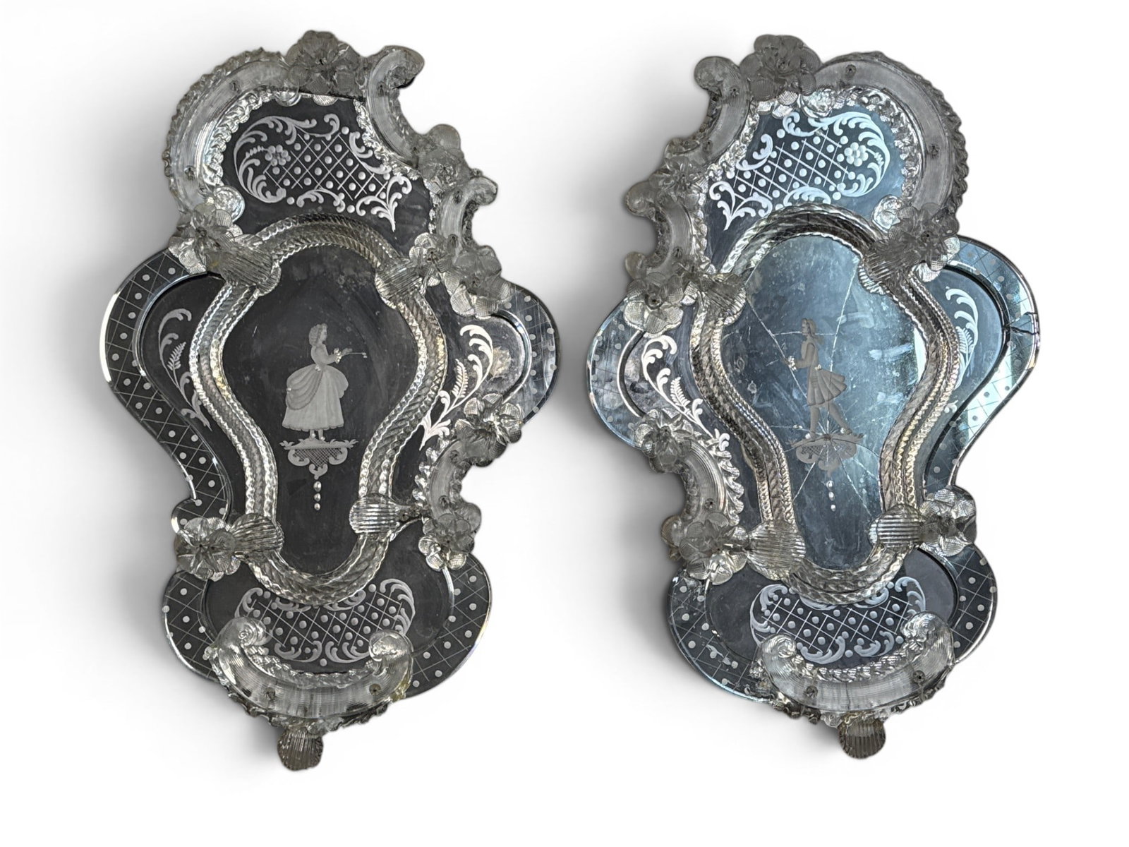 Pair of Figural Etched Venetian Glass Wall Mirrors: A pair of Venetian etched wall mirrors with shaped forms and central figural designs. Each: 27-1/2in tall x 17in wide. One with cracks as shown. Some additional losses and wear. | You have additional