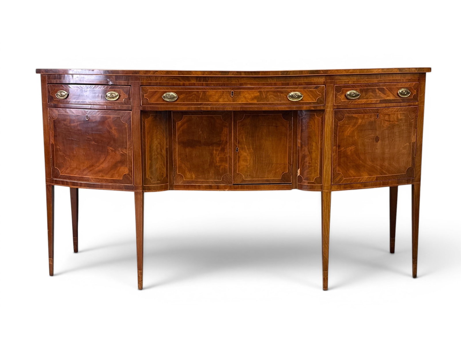 Hepplewhite Inlaid Mahogany Bowfront Sideboard: A Hepplewhite banded and inlaid mahogany bowfront sideboard, circa late 18th C., with a set of drawers over cabinets, raised on tapering legs. Provenance: From a Main Line, PA Private Collection. Ex.