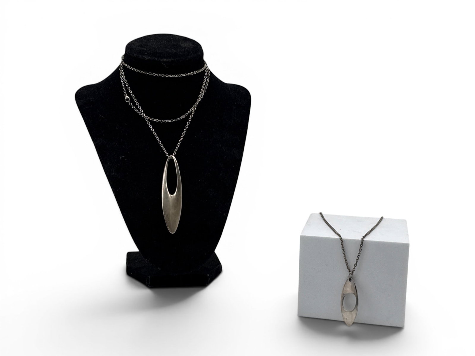 Two Georg Jensen Sterling Zephyr Necklaces: Two Georg Jensen sterling silver modernist necklaces to include a pattern 500 Zephyr pendant designed by Regitze Overgaard, and pattern 390 Mobius oval pendant. Each on a sterling silver chain. Larger
