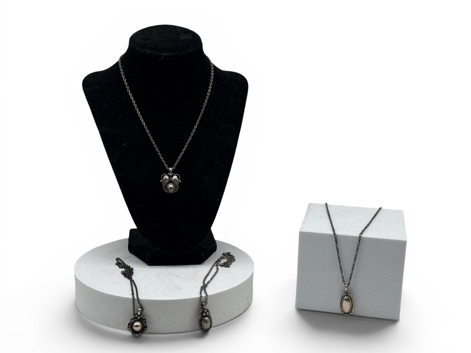 Four Georg Jensen Sterling Silver Pendant Necklaces: Four Georg Jensen sterling silver pendants with stylized designs, each hallmarked and on sterling chains. Pendants: 1in tall x 1in wide. 1.32 ozt. | You have additional shipping options, and are not r