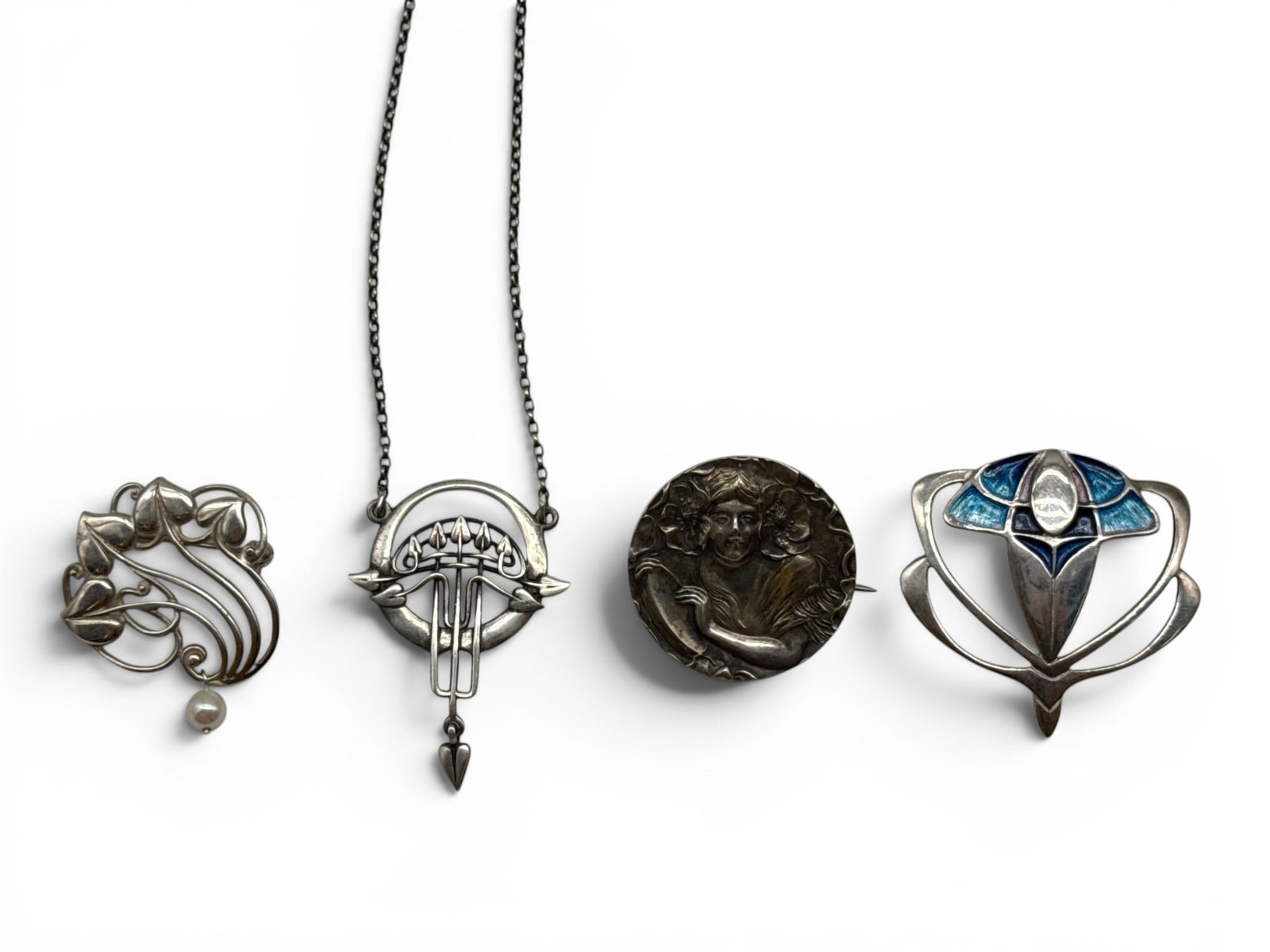 Grouping of Four Pendants and Brooches: To include an early 20th C. Charles Horner blue enamel and sterling silver stylized pendant; a Malcolm Gray silver botanical pendant and chain; and two sterling silver Art Nouveau brooches. Largest:
