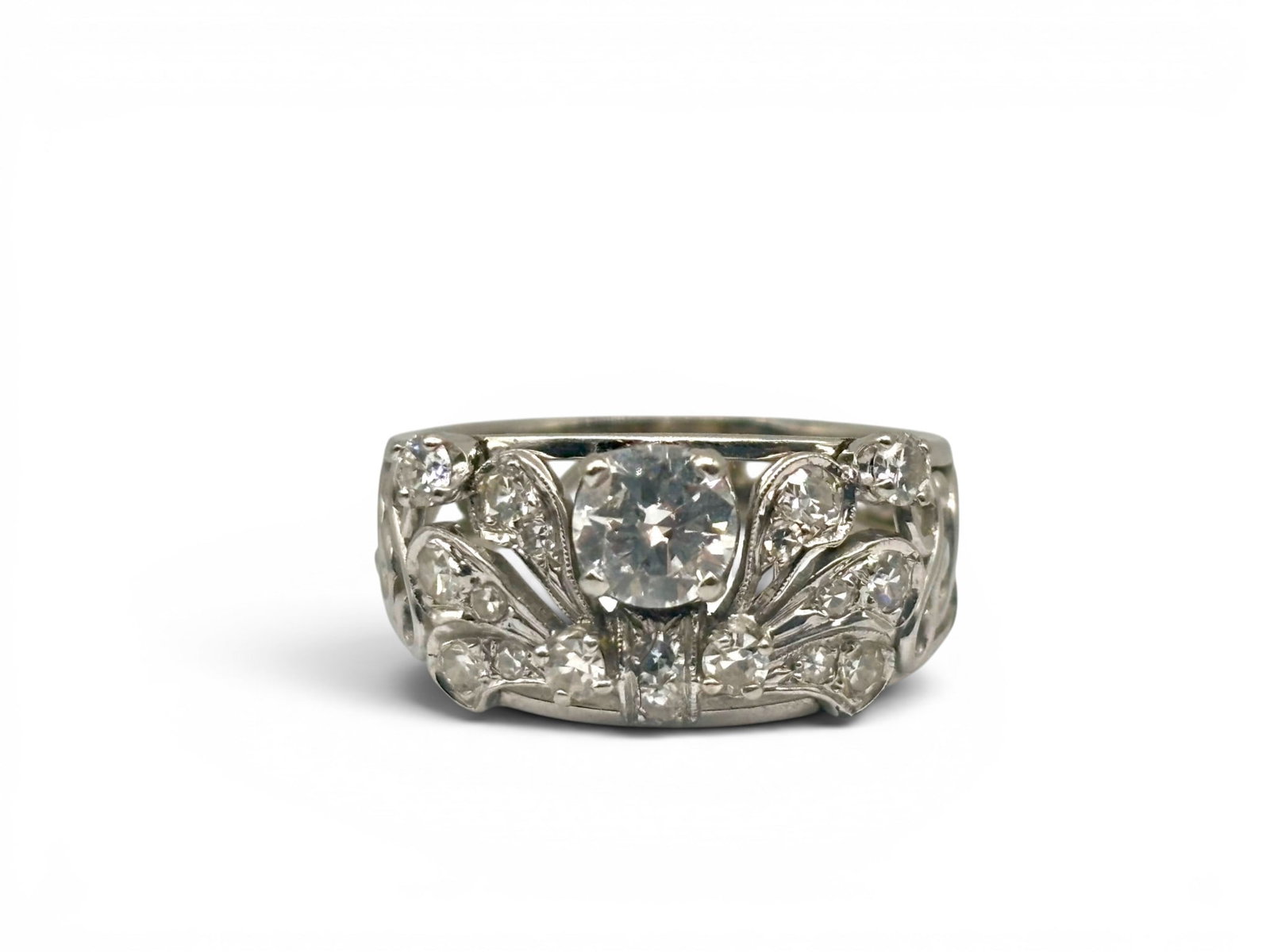 14K Art Nouveau-style Diamond Ring: A 14K white gold Art Nouveau-style diamond ring of half-anniversary style in an open swirled pattern on tapering shoulders with diamonds arranged on the head of the band in a floral pattern: a 0.56ct;