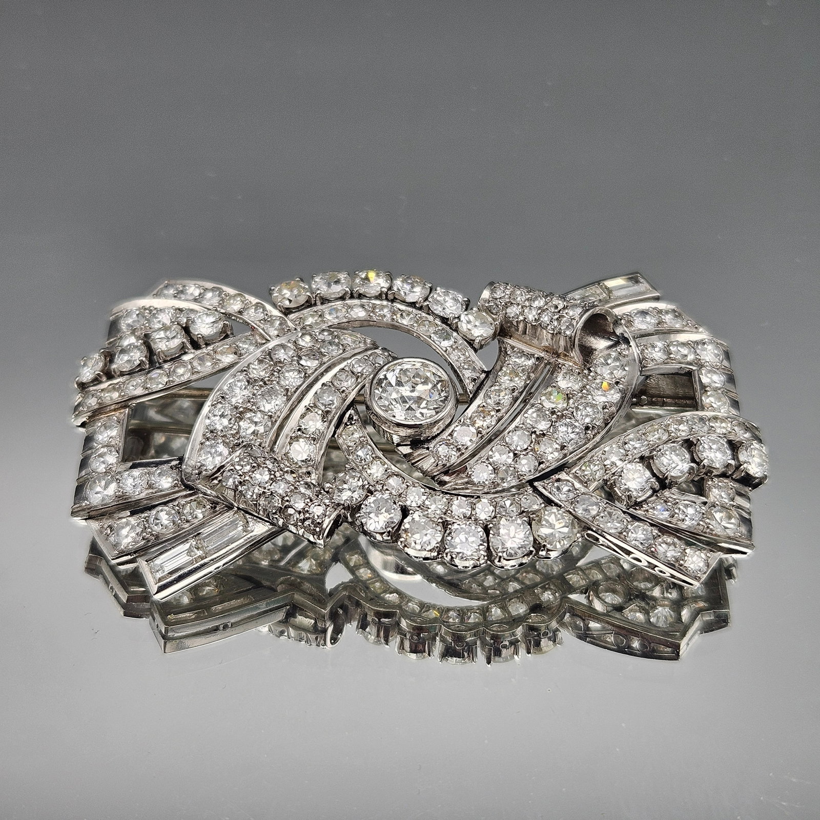 Art Nouveau Platinum and Diamond Brooch: An Art Nouveau platinum brooch of openwork design with a center diamond surrounded by baguette and round cut diamonds. TDW: 11.45 ct. 14.53 dwt. | You have additional shipping options, and are not req