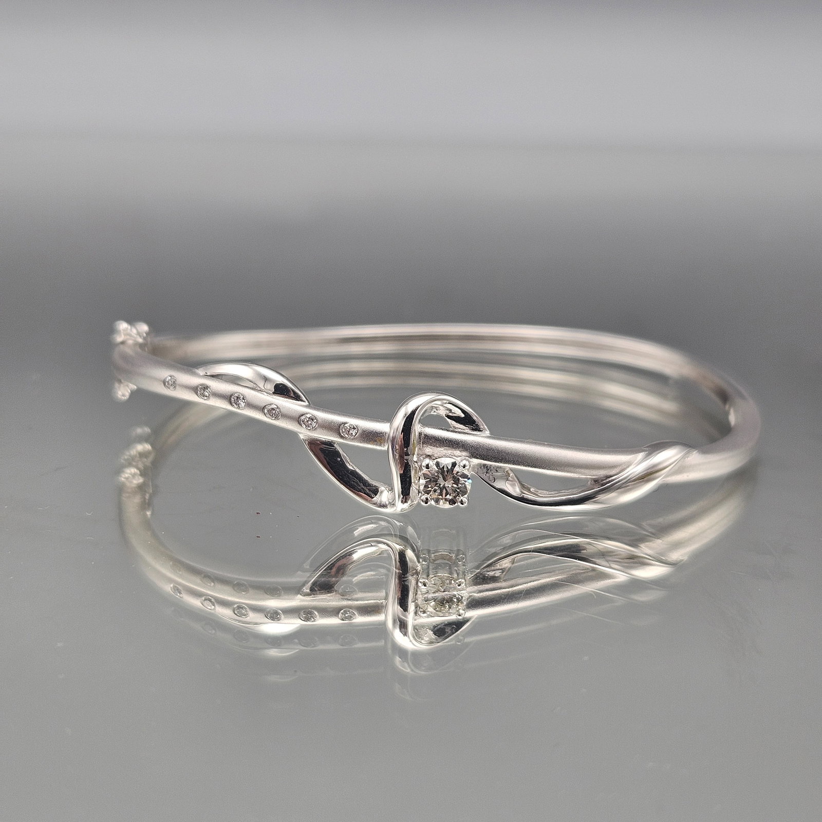 White Gold and Diamond Bracelet: A white gold bracelet of abstract design with a central diamond and four side diamonds. 6.68 dwt. | You have additional shipping options, and are not required to use Live Shipping. Additional shipping