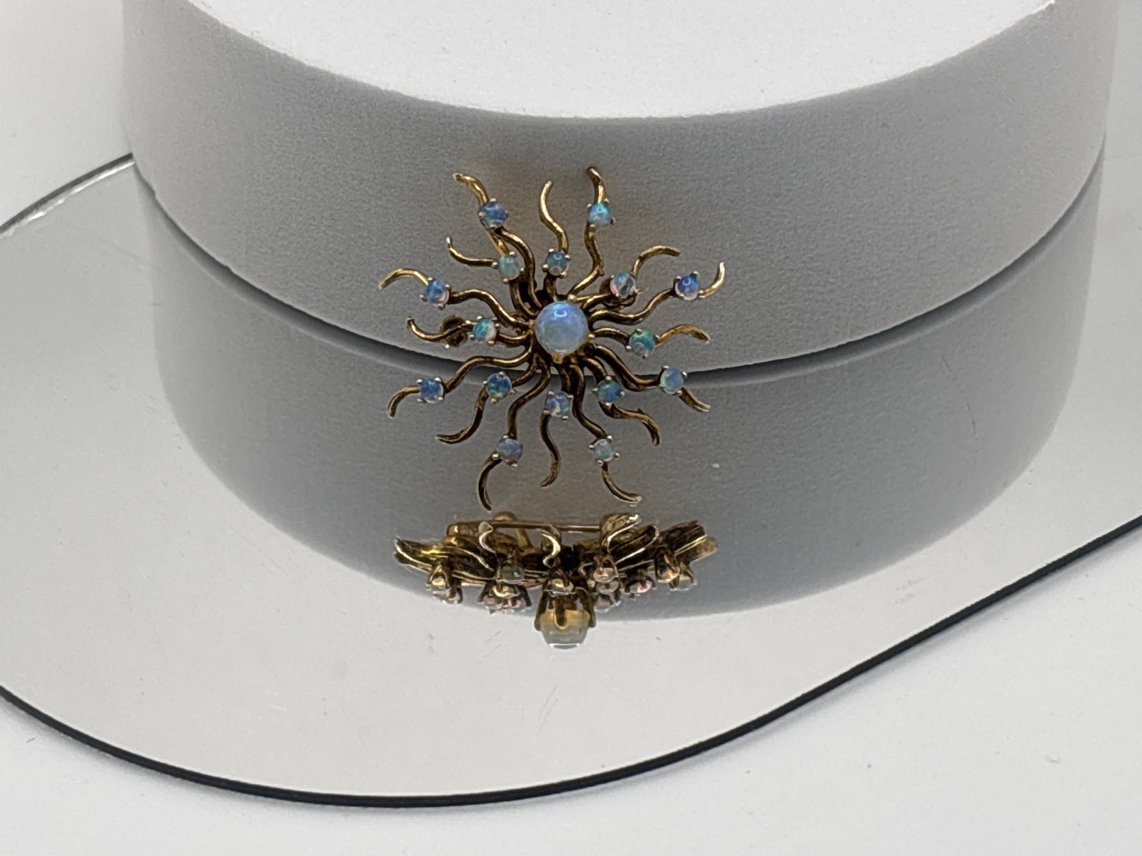14K Yellow Gold and Opal Sunburst Pendant/Pin: A 14K yellow gold (tested) spoked sunburst pendant pin with a central 4.4 mm opal cabochon surround by sixteen 2.2mm opal cabochon accents. 1-1/4in diameter. 3.74 dwt. One accent opal is chipped. | Yo