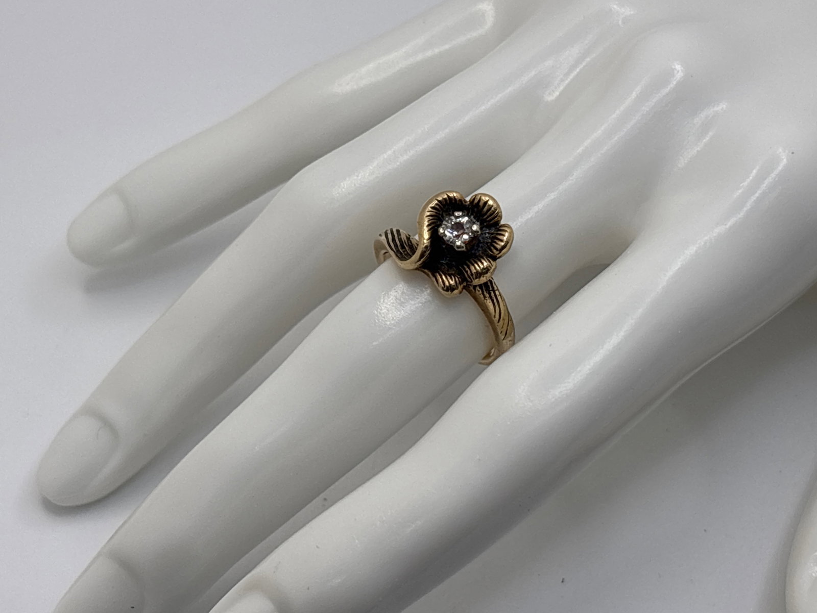 14K Yellow Gold Nouveau-style Flower Form Ring: A 14K yellow gold curvilinear flower form ring with the band appearing to wrap around as a stylized stem, set with a 3.8mm diamond at the center of the bloom. Stamped 14K. 3.77 dwt. | You have additio