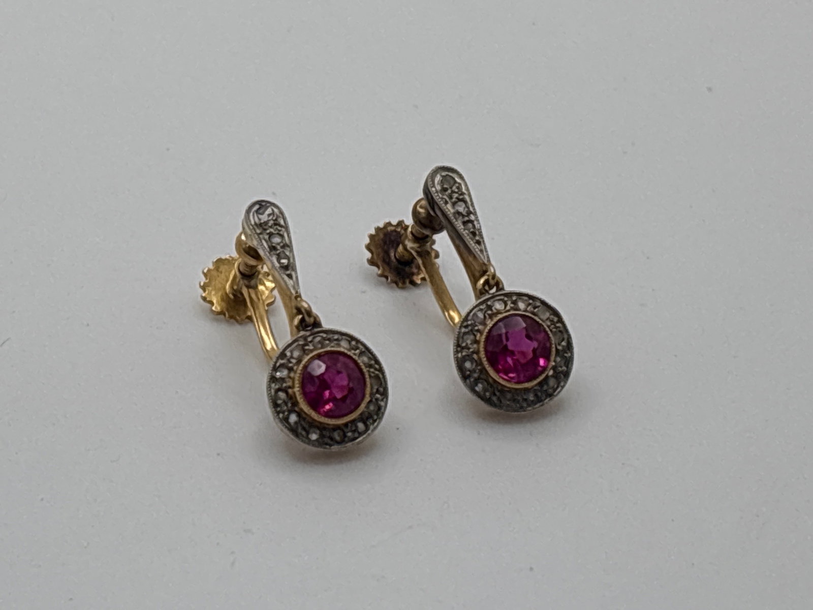 14K Ruby and Diamond Halo Earrings: A pair of 14K (tested) screw-back earrings, each with a 4.6mm bezel-set ruby in a pav? diamond surround, in a Michael Kyrollos 21 Salah Salem Alexandria box. 3/4in tall overall. 2.17 dwt. | You have