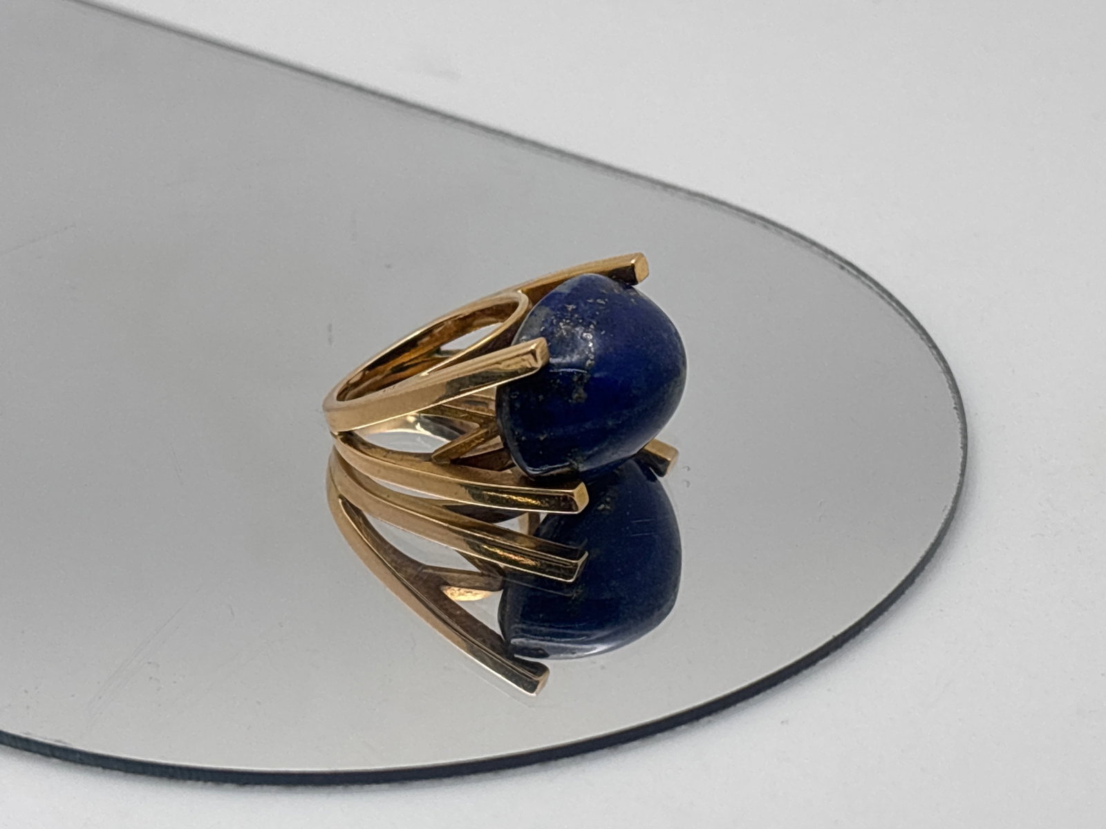 18K Lapis Cabochon Cocktail Ring: An 18K yellow gold modernist ring set east-west with a 21mm x 15.3mm x 12mm H lapis cabochon. Marked 18K with Egyptian hallmarks. Ring size 5. 9.34 dwt. | You have additional shipping options, and