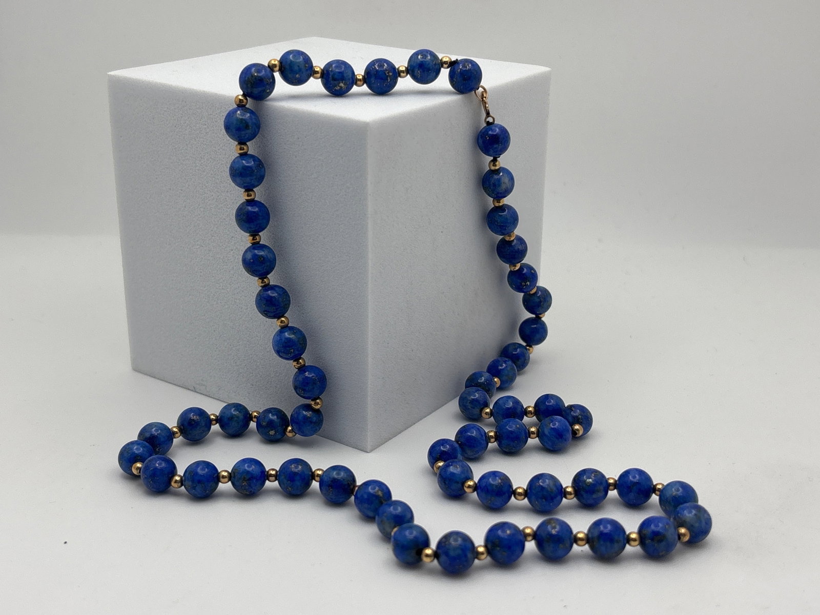 14K Yellow Gold and Polished Lapis Necklace: A hand knotted strand of polished 8mm lapis beads interspersed with 14K spacers. Marked 14K on clasp. Retailed by Wanamaker. 24in long. | You have additional shipping options, and are not required to 