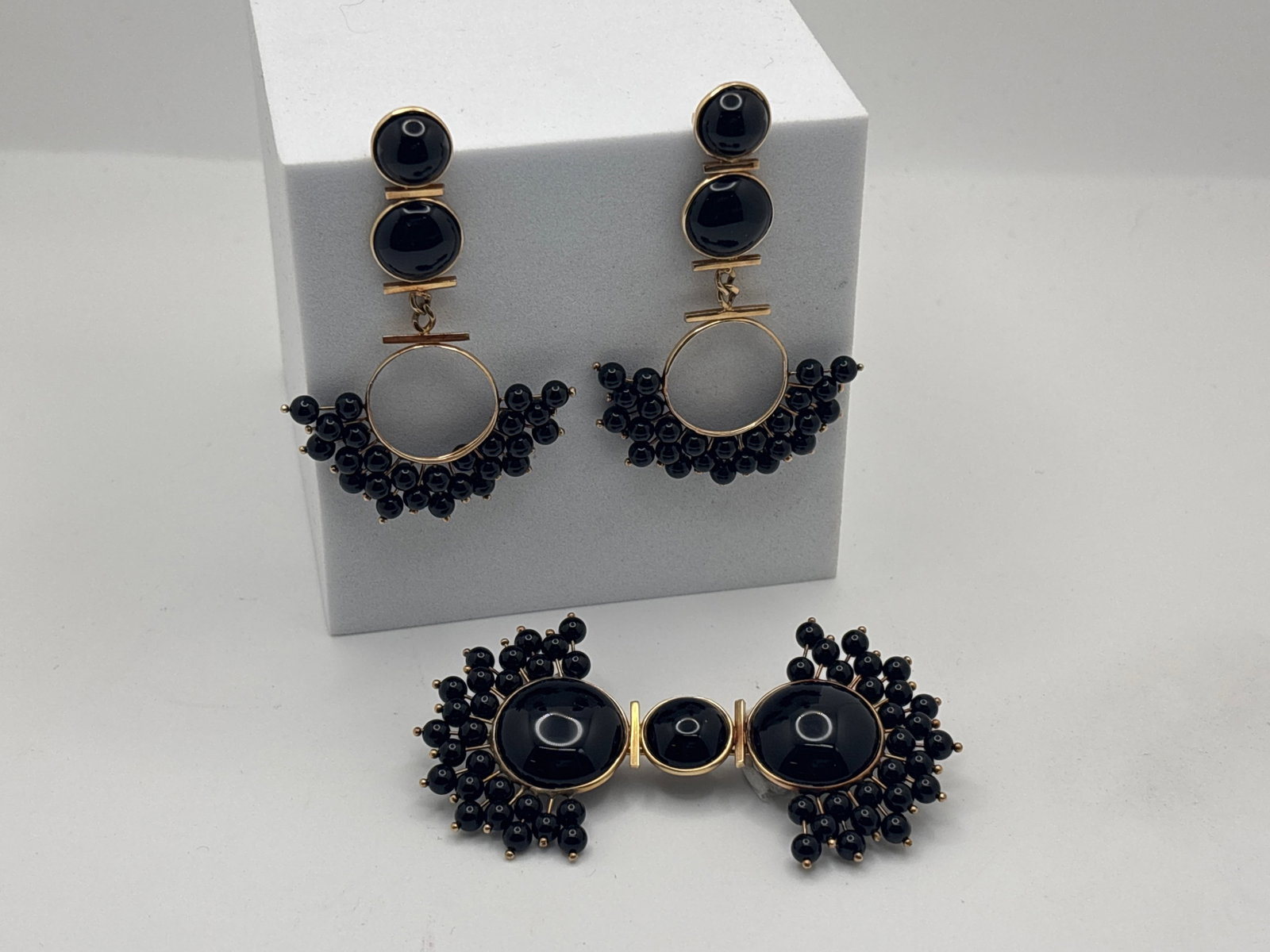 14K Yellow Gold & Black Onyx Demi-Parure: A 14K yellow gold and black onyx brooch with clustered polished onyx bead trimmed ends, 1-5/8in tall x 2-7/8in long; and a pair of matched onyx and polished clustered onyx bead fringed statement