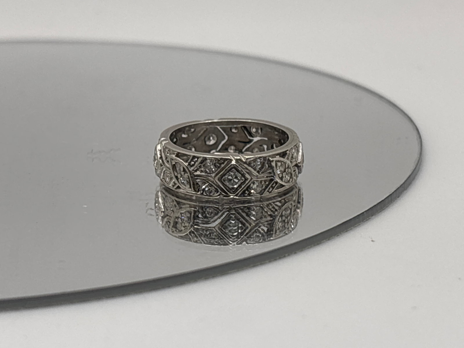 Art Deco Platinum and Diamond Filigree Ring: An Art Deco platinum (tested) band ring with round cut flush-set diamond surround in a stylized leaf and geometric design. Ring size 6.25. 3.71 dwt. | You have additional shipping options, and are