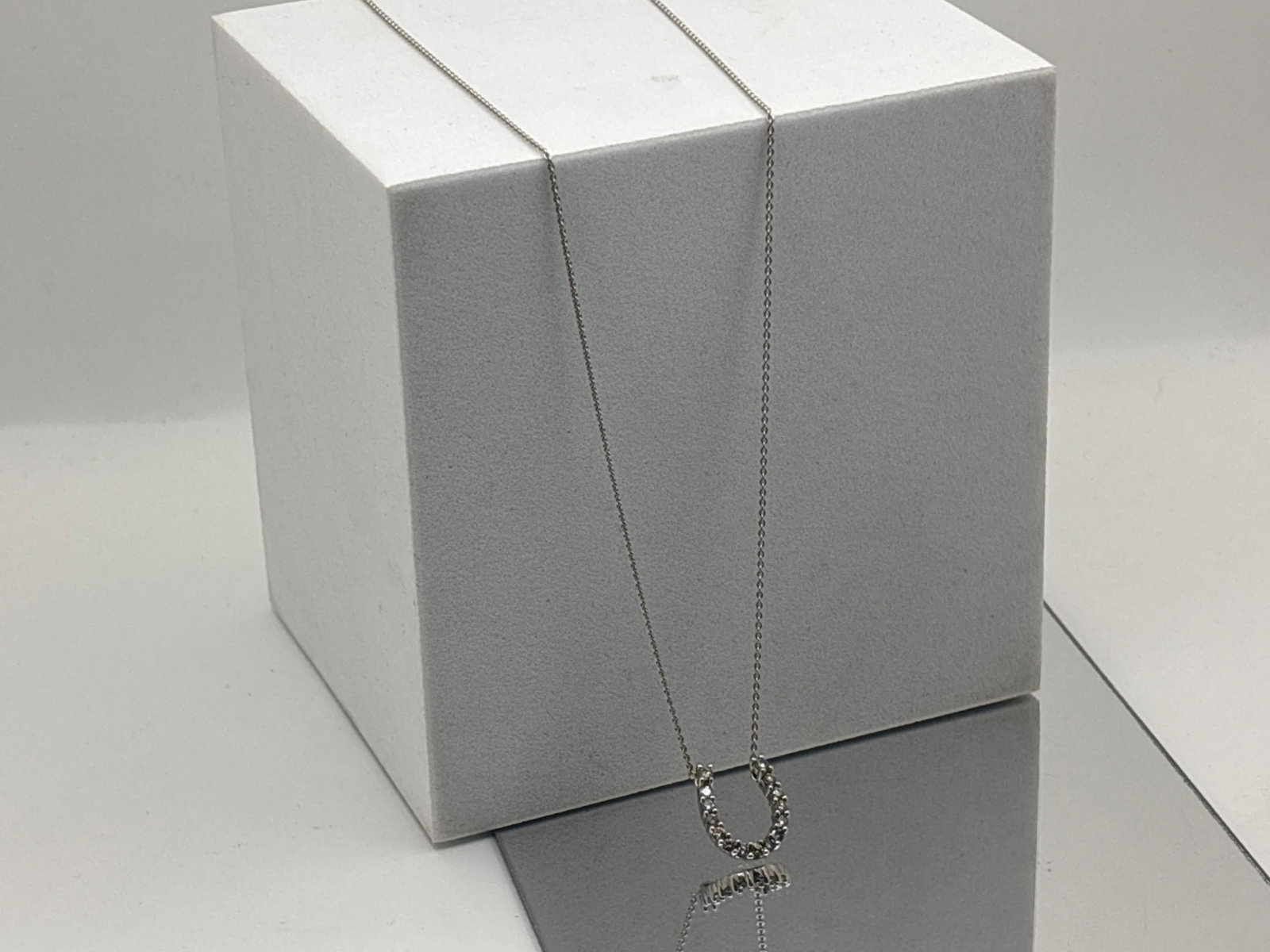 14K White Gold Diamond Horseshoe Pendant: A 14K white gold chain with a fixed diamond horseshoe pendant at center, comprised of fifteen 1.9mm round cut diamonds. Stamped 14K on clasp. 17-3/4in long. 1.94 dwt. | You have additional shipping