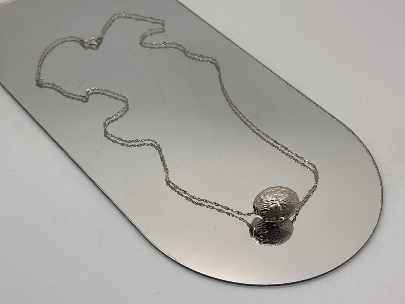 14K White Gold Bright Cut Bead Necklace: A bright cut hollow-bodied slide bead pendant suspended on a 14K white gold chain. Signed "SLC" at closure, stamped Italy and 14K. Chain: 18in long. Beads: 3/4in long. 1.69 dwt. | You have additional 