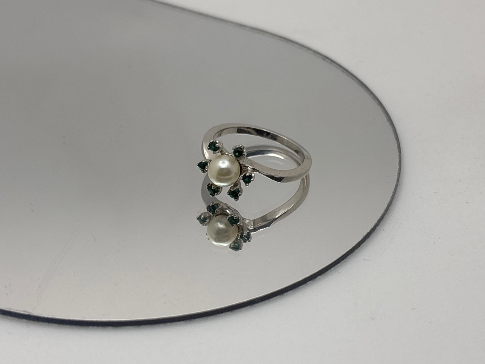 14K Flower Ring with Pearl and Tourmaline: A14K white gold flower-form ring set with a 5.1mm central pearl with six 1.8mm round cut blue-green tested tourmaline "petals" surrounding. Marked 14K on interior shank with maker's mark "R.C." Ring