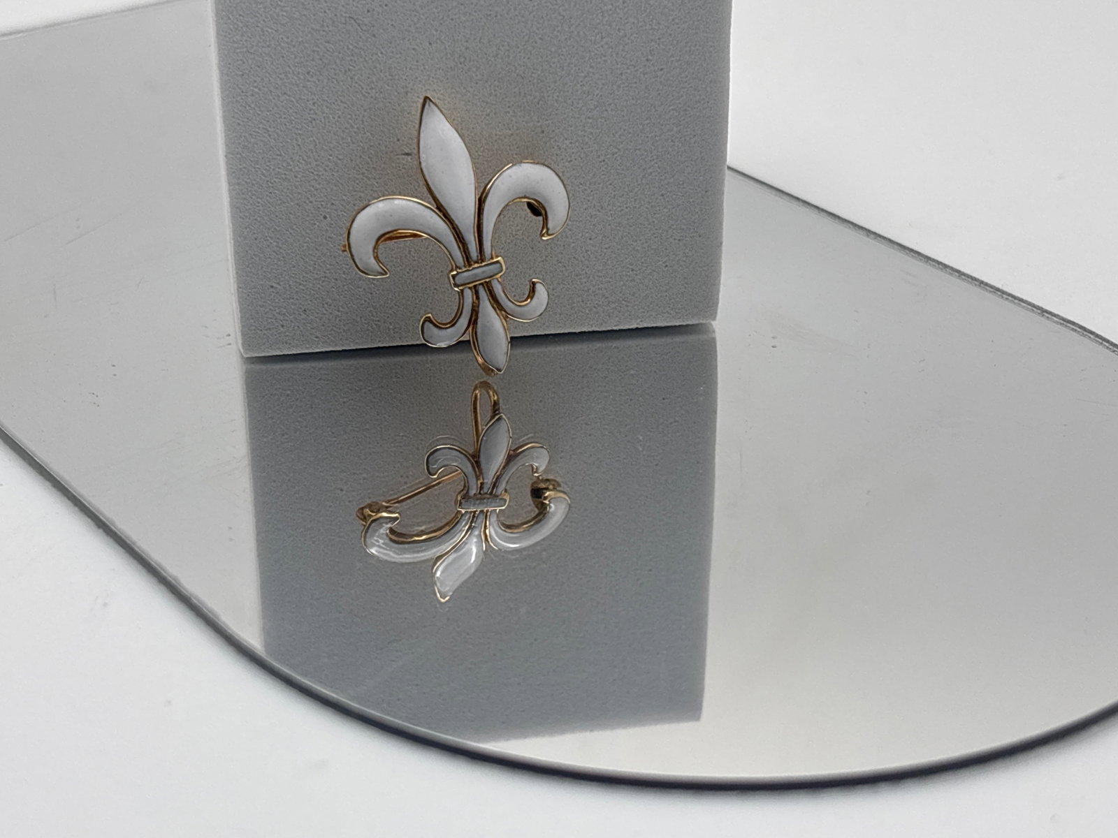 14K Enameled Fleur-de-Lis Watch Pin: A 14K yellow gold fleur-de-lis watch pin with white enamel. Stamped 14K on back with remnant maker's mark behind watch hook. 1-1/8in tall x 1in wide. 2.58 dwt. | You have additional shipping options, 