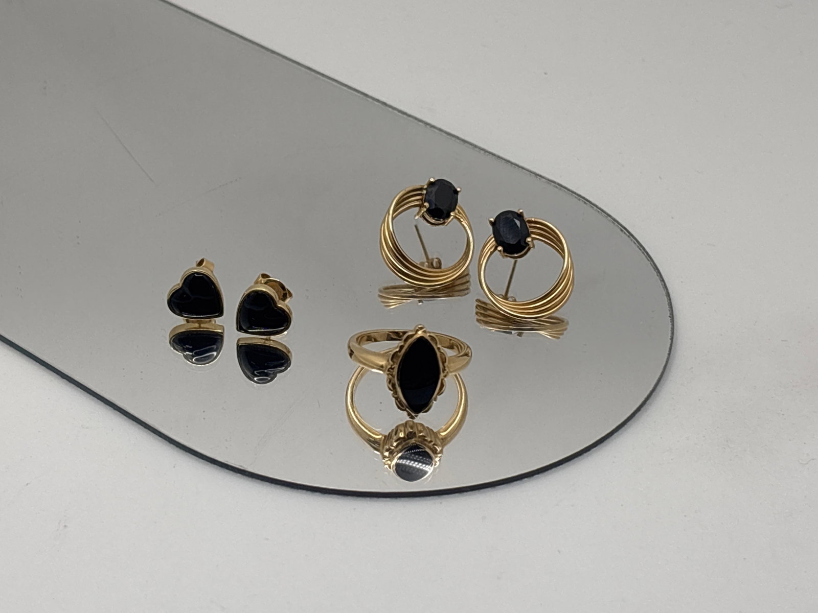 14K Onyx Set Earrings and Ring Grouping: Five pieces of 14K yellow gold set with onyx to include a pair of heart-shaped post earrings, a pair of textured hoop earrings with oval cut onyx, and a mid-20th C. Ring, size 6. Hoops: 3/4in tall. 6.