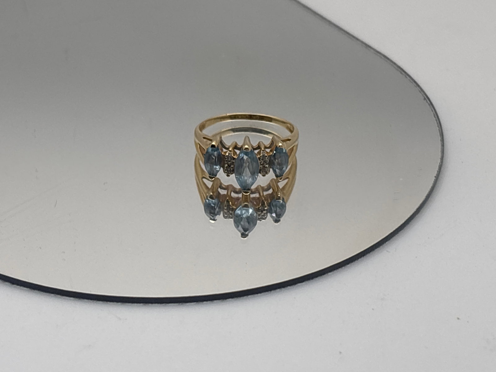 14K Yellow Gold and Blue Topaz Ring: A 14K yellow gold (tested) ring set with a central marquise-cut blue topaz of 7.5mm x 4.1mm flanked by a 4.7mm x 2.3mm blue topaz on either size, with diamond accents. Ring size 6. 1.58 dwt. | You hav