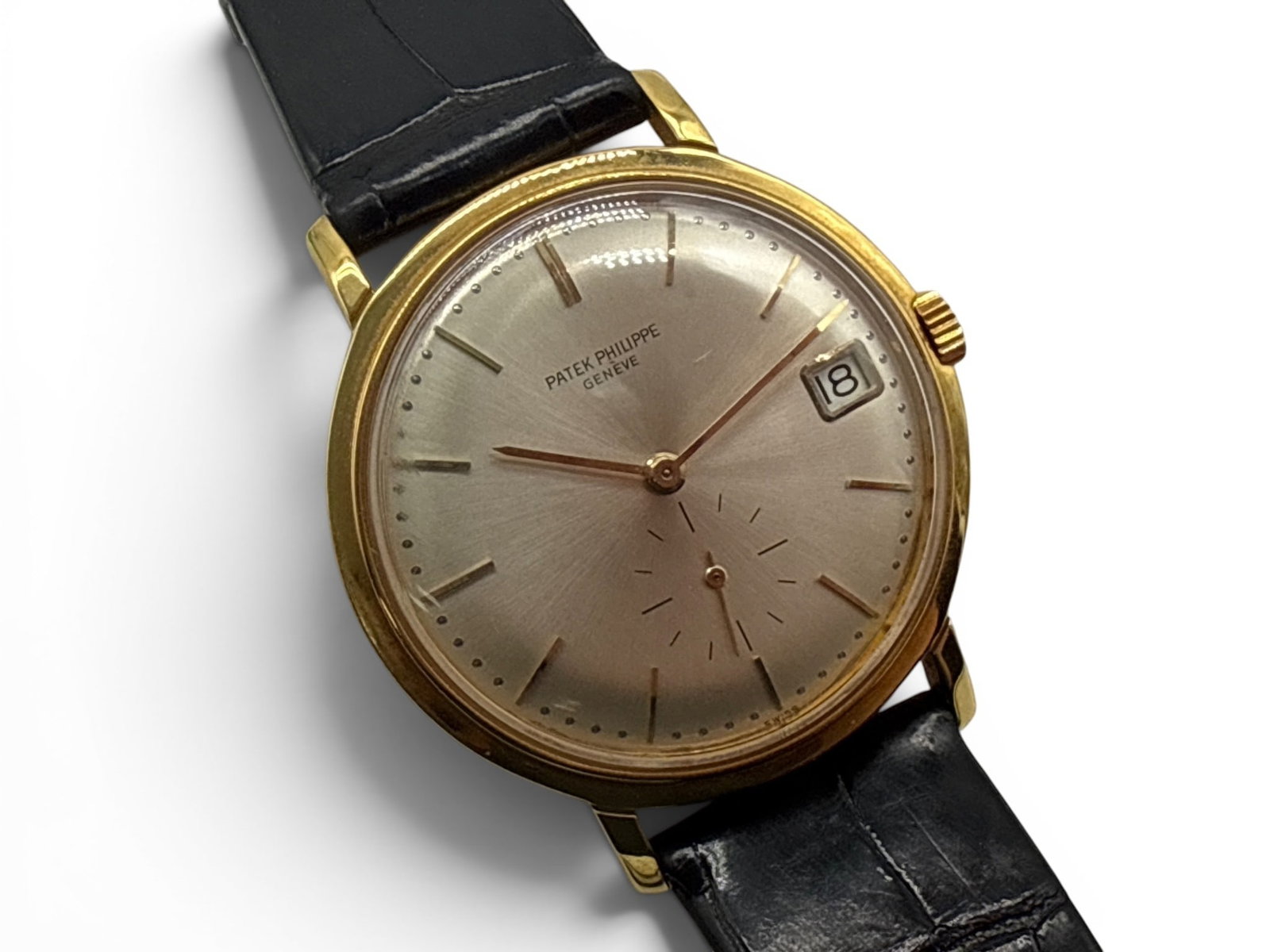 Patek Phillipe 18K Yellow Gold Calatrava Wristwatch: A Patek Phillipe 18K yellow gold Calatrava watch, reference 3445, with a silver sunburst dial, gold bar hour indexes, date aperture at 3 o'clock, small seconds at 6 o'clock, and gold baton hands, powe