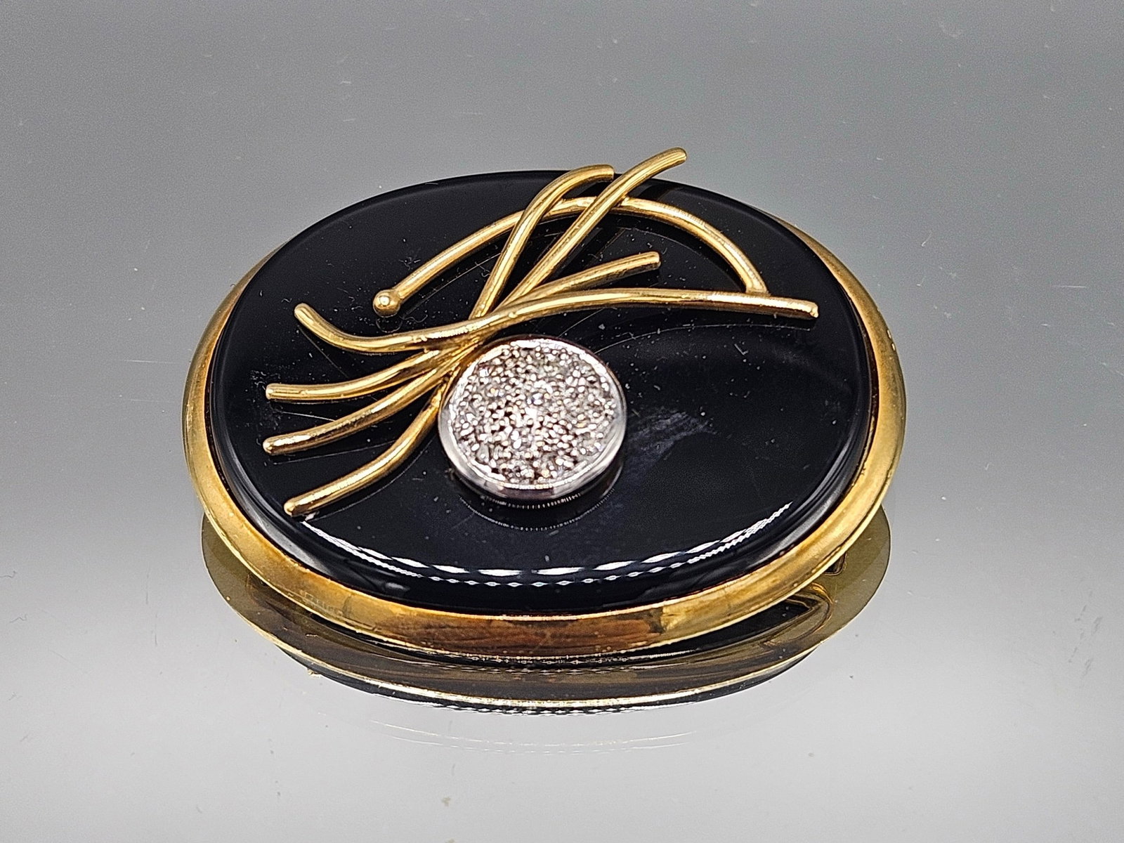 Modernist 14K Brooch with Onyx and Pave Diamonds: A 14K yellow gold modernist brooch with onyx, applied gold decoration, and pave diamond center. Marked 14K. 1in tall x 1-1/2in wide. 8.48 dwt. | You have additional shipping options, and are not requi