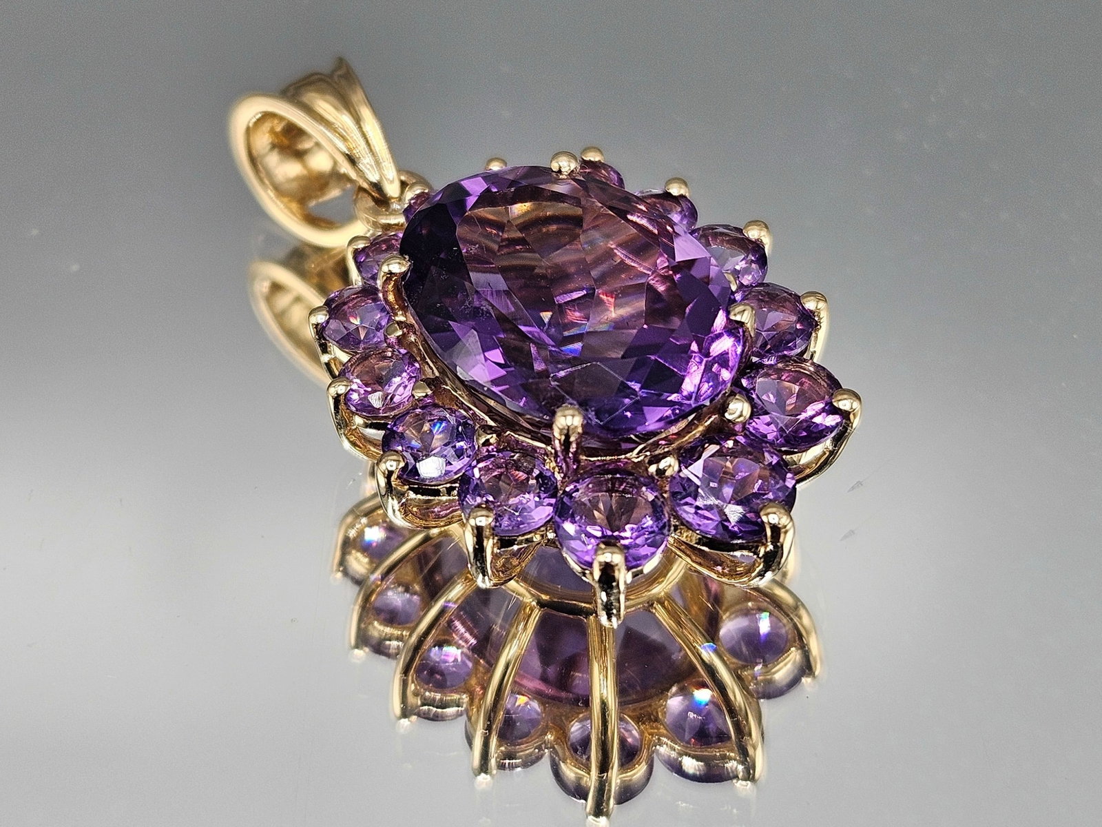 14K Amethyst Halo Pendant: A 14K yellow gold pendant featuring a large oval cut amethyst surrounded by fourteen round cut amethysts. Marked 14K. 4.56 dwt. | You have additional shipping options, and are not required to use Live