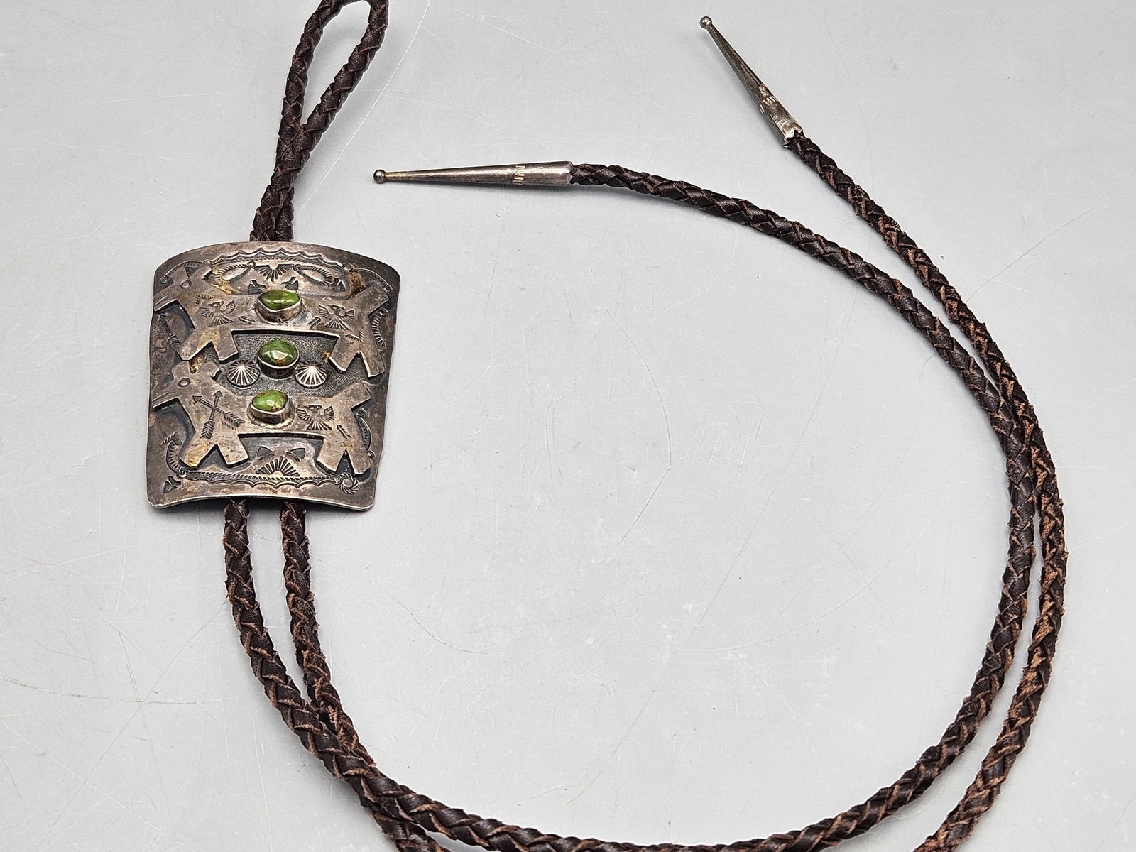 Jeanette Dale Silver and Turquoise Bolo Tie: A Jeanette Dale Navajo silver bolo tie with applied dog-form figure and three turquoise cabochons. Signed. 21-1/2in long. 40.10 dwt. | You have additional shipping options, and are not required to use