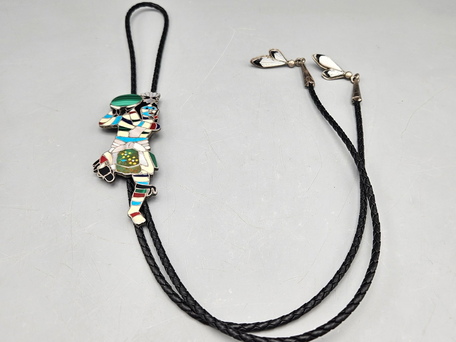 Zuni Kachina Dancer Bolo Tie: A Zuni silver and inlaid stone bolo tie with Kachina dancer form. 22in long. Figure: 4in tall x 1-1/2in wide. 30.98 ozt. | You have additional shipping options, and are not required to use Live Shippi