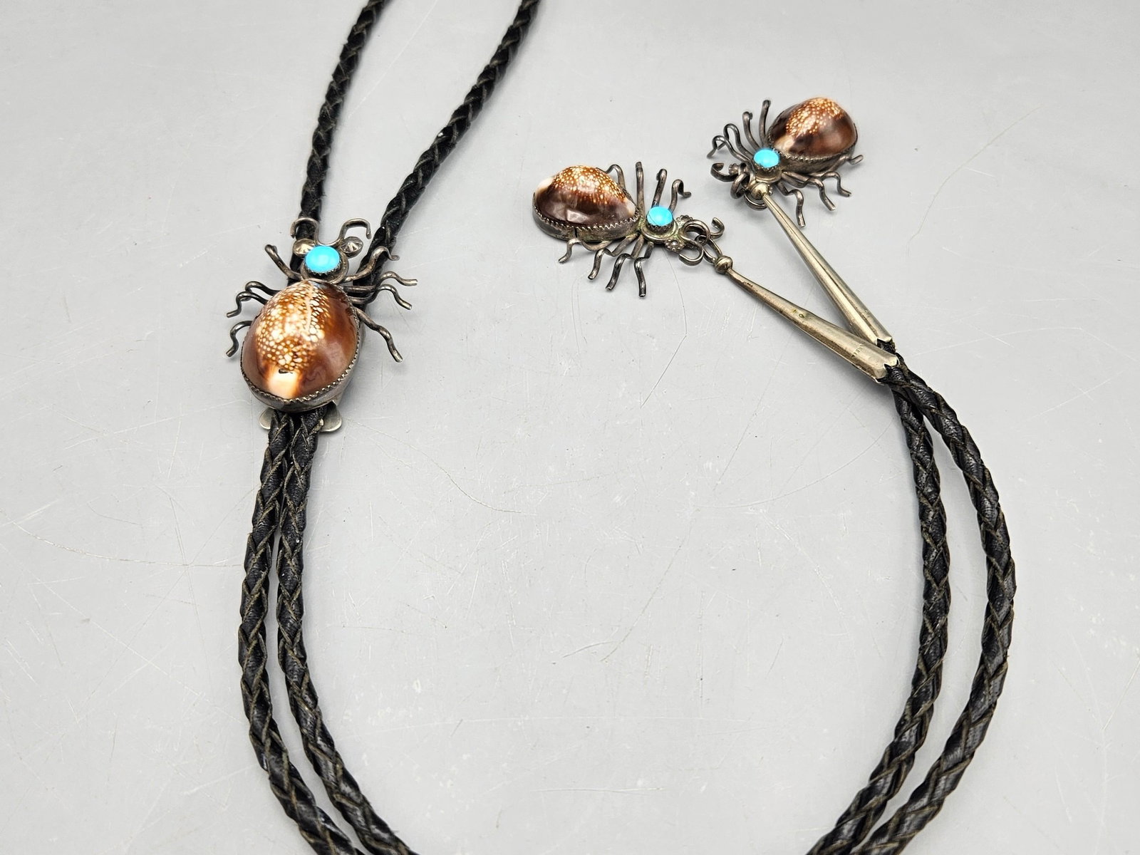 Navajo Silver and Shell Spider Bolo Tie: A Navajo silver bolo tie with spider-form slide and tie caps with turquoise and shell. 20in long. Spider: 2in tall x 1in wide. 32.81 dwt. | You have additional shipping options, and are not required t