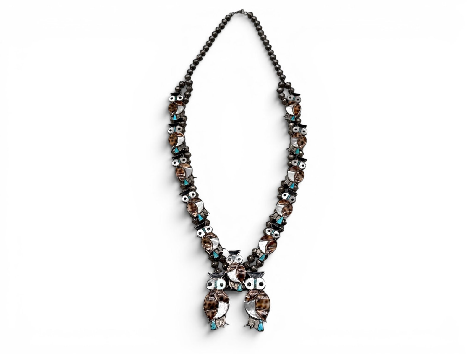 Zuni Silver Owl Squash Blossom Necklace: A Zuni silver squash blossom necklace with three owl forms with inlaid turquoise, mother of pearl, onyx, and shell. 30in long. Naja: 3-3/4in long x 2in wide. 75.42 dwt. | You have additional shipping 