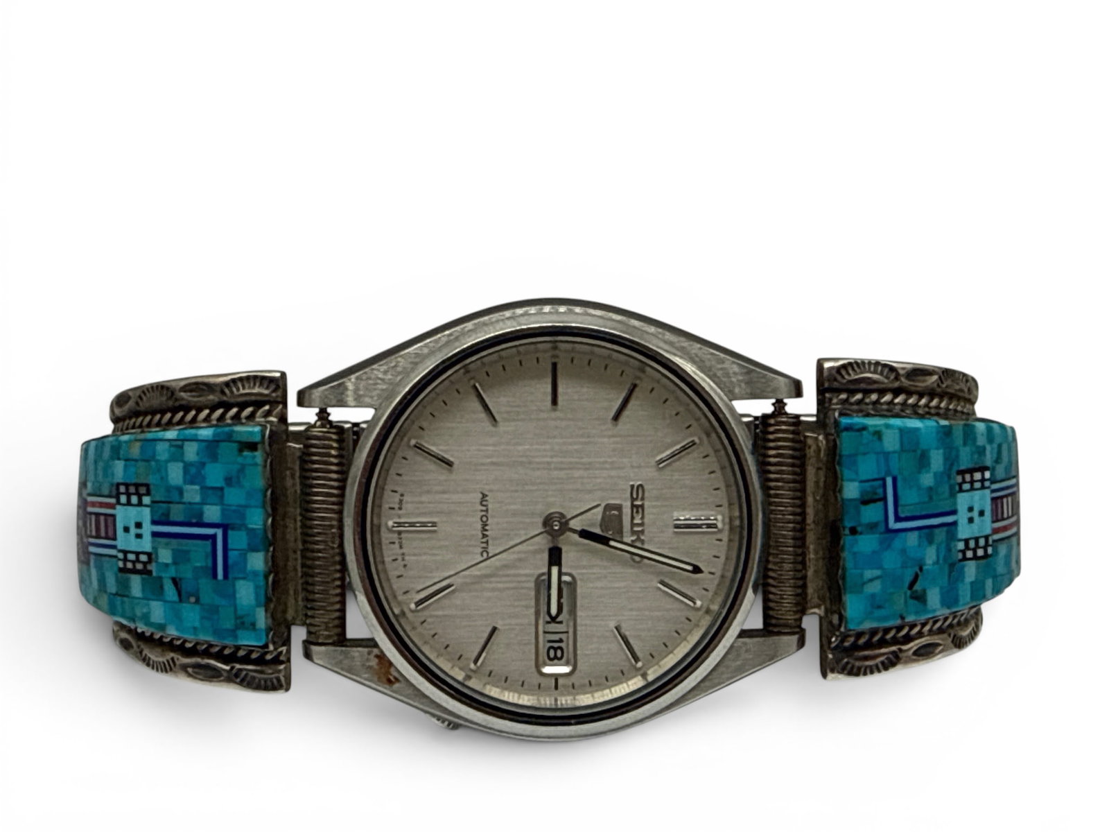 Seiko Chester Nez Sterling Wristwatch: A Seiko Chester Nez-design (Navajo, 1921-2014) sterling wristwatch inlaid with turquoise, onyx, lapis lazuli, and coral, on a silver band. Signed. Band: 3-1/2in diameter. | You have additional shippin