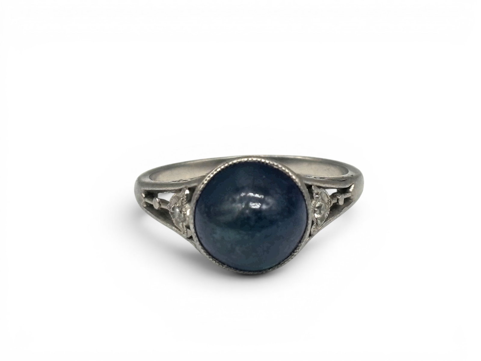 14K White Gold Ring with Sapphire and Diamonds: A 14K white gold ring with central domed sapphire in a raised filigree setting surrounded by two small diamonds set in floral-form shoulders. Size 4-1/2. 2.18 dwt. | You have additional shipping optio