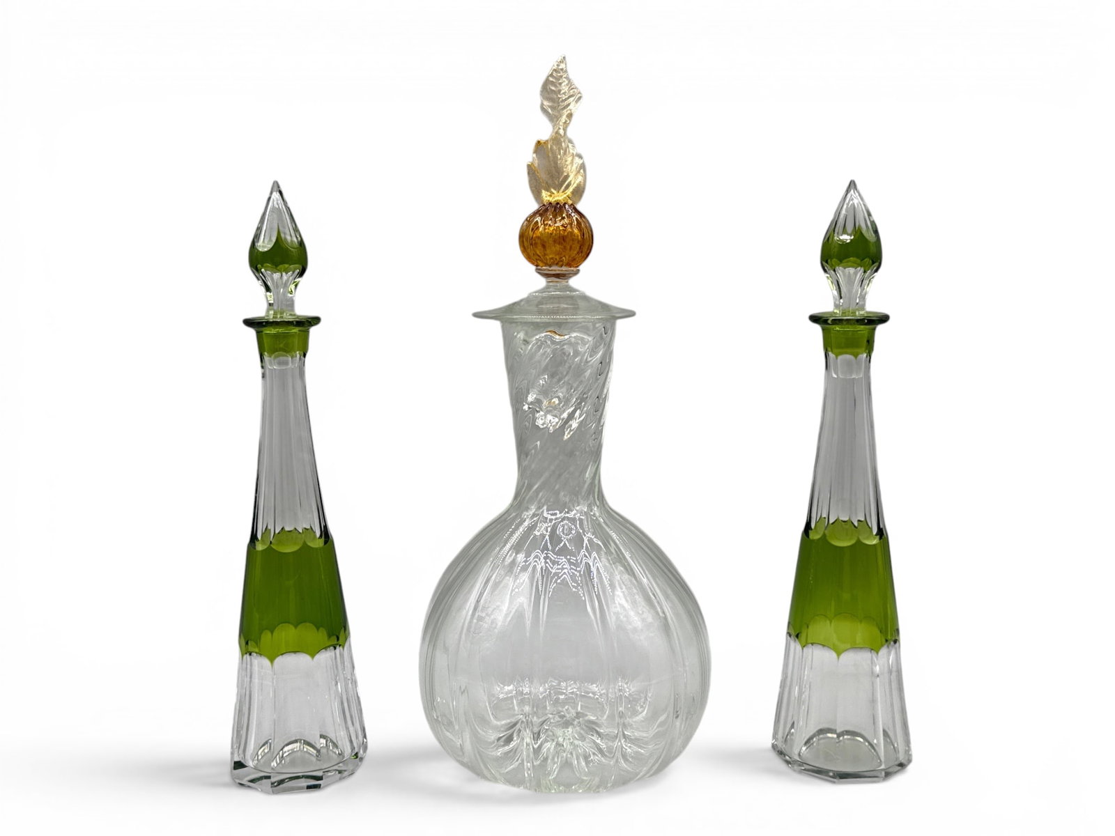 Pair of Val St. Lambert and Venetian Decanters: A pair of signed Val St. Lambert chartreuse green and clear crystal decanters, and a blown glass swirled decanter with twisted Venetian glass finial. Larger: 15in tall x 6in wide. | You have additiona