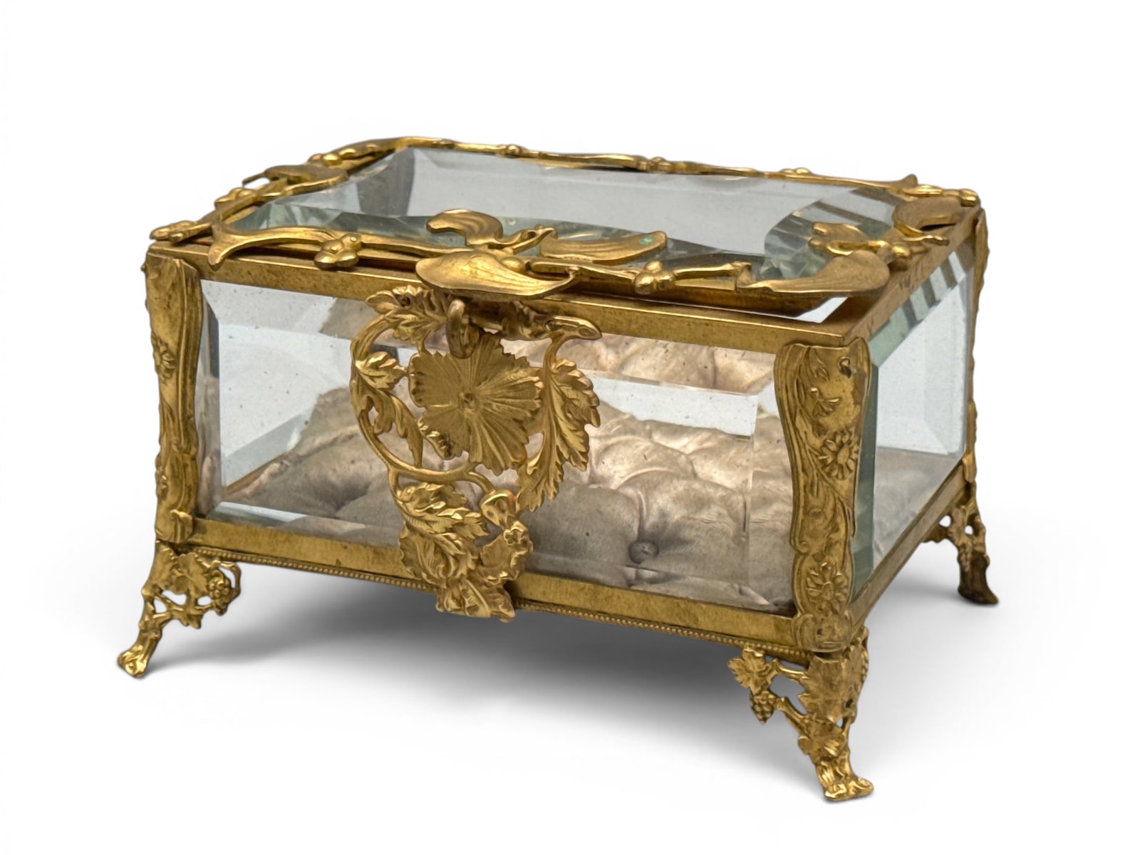 French Art Nouveau Gilt Bronze Casket: A French Art Nouveau gilt bronze jewelry casket with beveled glass panels, tufted silk interior, and stylized floral decoration, resting on grape leaf feet. 3in tall x 5in wide x 3-1/2in deep. | You h