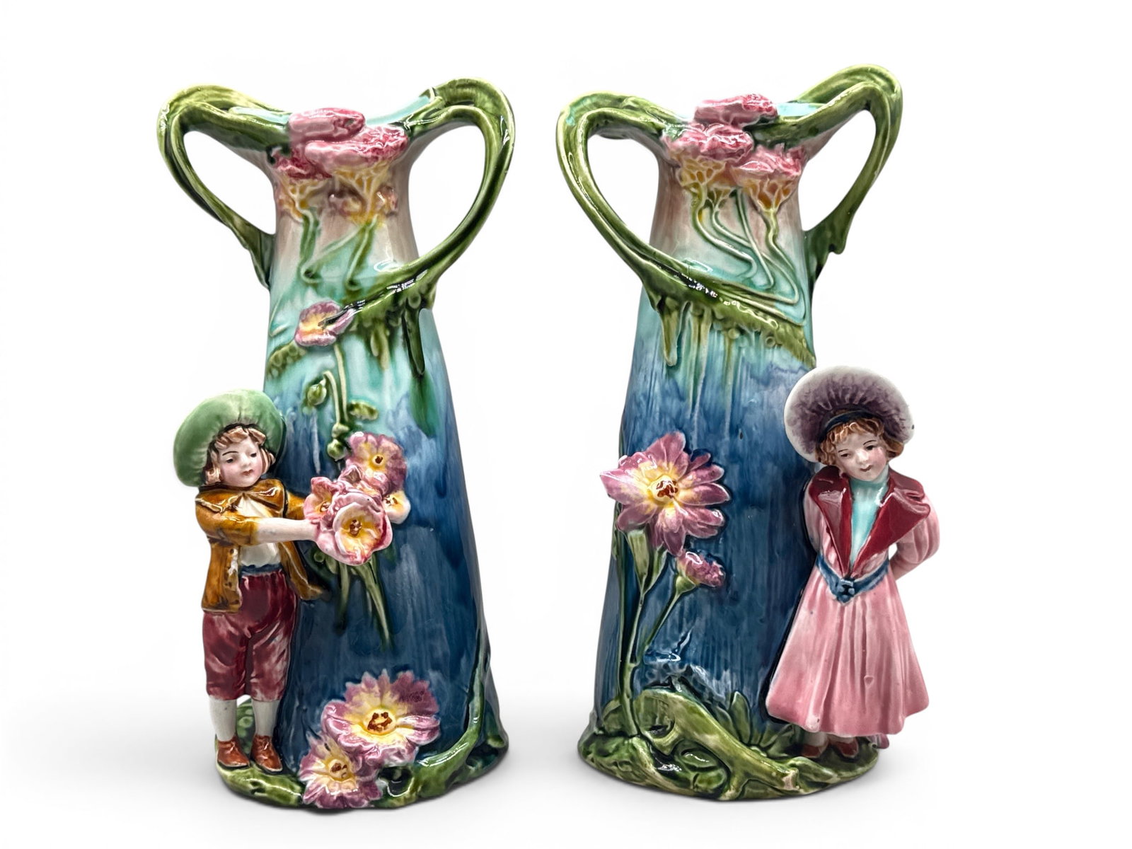 Pair of Art Nouveau Majolica Figural Vases: A pair of Art Nouveau majolica pottery vases with stylized floral design and young Dutch boy and girl figures. One bears T.C. Brown marking and is numbered 8642. 11in tall x 5in wide. | You have addit