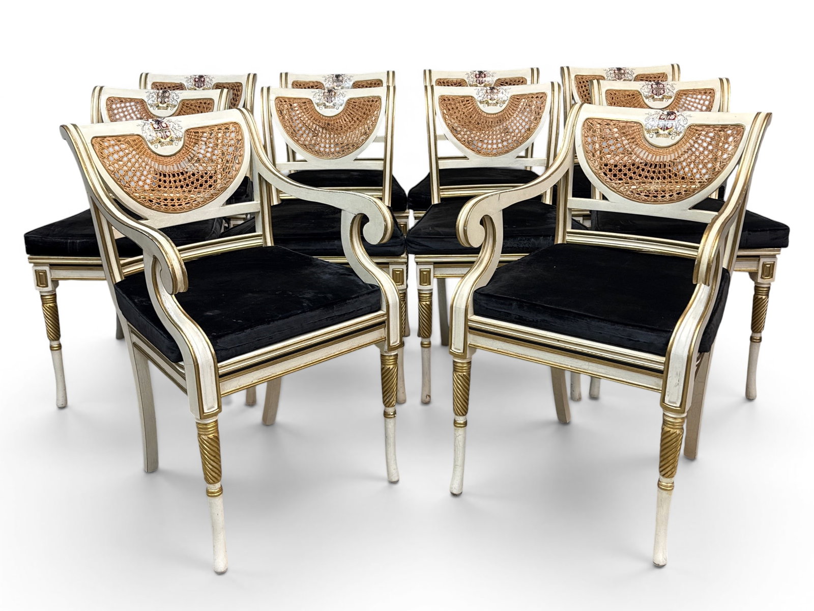 Ten Regency-style Clive Christian Chairs: A set of ten Regency-style paint-decorated dining chairs, attributed to Clive Christian, with armorial crest decoration over half-round caned backs, cushions over caned seats, and carved and painted c