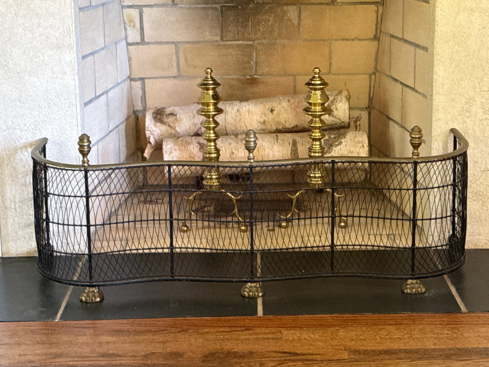 Brass Wirework Fire Fender and Pair of Andirons: A serpentine-form brass and wire fire fender with paw feet and a pair of Chippendale-style brass andirons. Fender: 15-1/2in tall x 42in wide x 13in deep. | You have additional shipping options, and